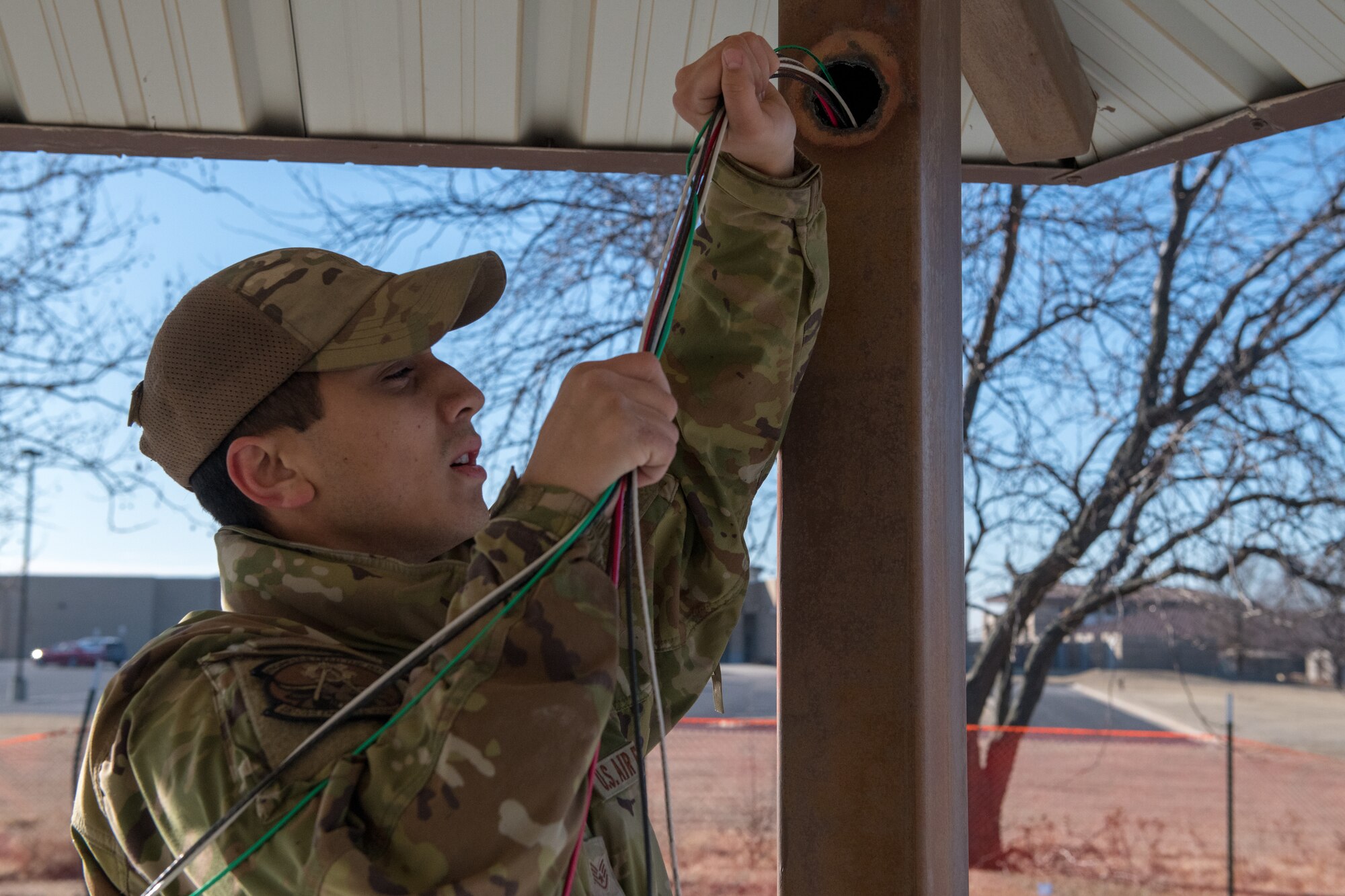 Staff Sgt. Daniel Doane, 22nd Civil Engineer Squadron power production craftsman, feeds wires into the gazebo in preparation for installing solar panels in the new Food Truck Park Feb. 2, 2023, at McConnell Air Force Base, Kansas. The 22nd CES has been working on a new Food Truck Park with plans to officially open in April. (U.S. Air Force photo by Airman 1st Class Felicia Przydzial)