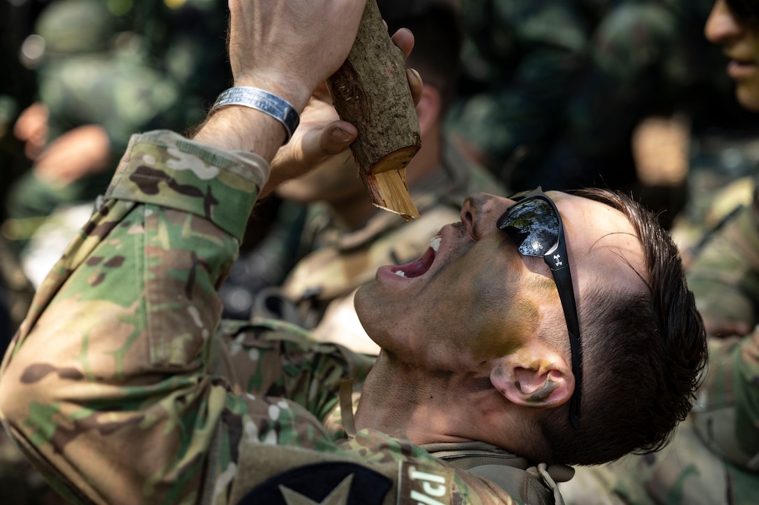 Close-up shot of a soldier drinking drops of water from a branch.