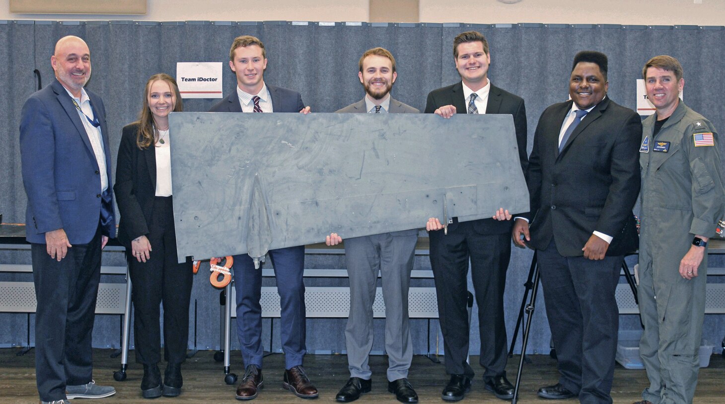 “TEAM iDOCTOR (Inspection and De-icing using Cold formation Thermal Object Recognition) at Naval Air Warfare Center Aircraft Division, Lakehurst, New Jersey, pose with an F/A-18 wing panel which was used as a test article as part of their work in identifying ice accumulation on aircraft as part of the team’s NAVAIR Innovation Challenge. From left is Stephen Cricchi, Executive Director NAWCAD, Sarah Bunn, Trevor Hinds, Stephen Opet III, Charles Homoki, Jonathan Alcantara and Rear Adm. John “Doc” Dougherty IV, Commander, NAWCAD.
