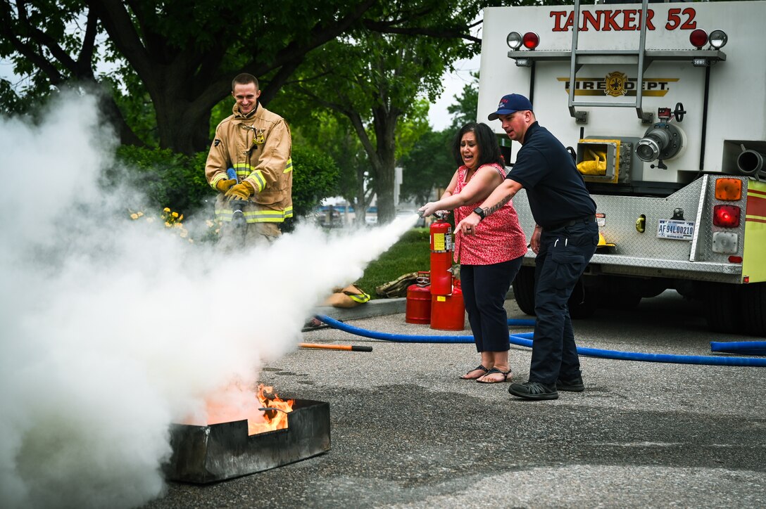 Lucinda Savala screams and extinguishes a pan fire with Airman 1st Class Ryan Shukis and Justin Matthes by her side, June 15, 2022, during Statewide Safety Day in Lincoln, Neb