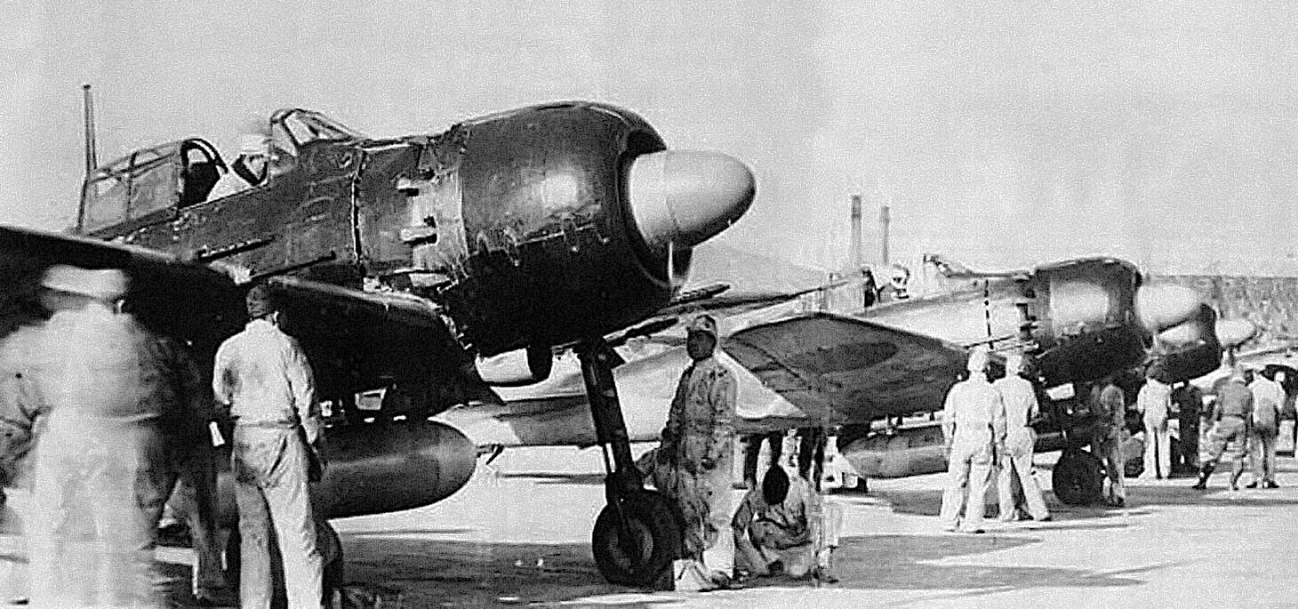 Pilots of a line-up of A6M5c Zeros on the flight line prepare to sortie from their base on Kyushu in 1945. This model of the Zero was among the most produced and also the most heavily armed, including three 12.7 mm machine guns (two in the wings, and one unseen in this photo, in the upper cowling, and one 20 mm cannon in each wing). By war’s end, the Zero was one of the most used aircraft in Kamikaze raids.