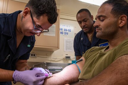 GULF OF THAILAND (March 4, 2023) –Hospitalman Anthony Gonzalez, left, draws blood from Hospital Corpsman 3rd Class Alaa El Saad,  assigned to 2nd Division, 4th Marines (2/4), 13th Marine Expeditionary Unit (MEU),during a walking blood bank exercise aboard amphibious transport dock USS Anchorage (LPD 23), March 4, 2023. Walking blood banks are held to prepare for an urgent mass casualty requiring blood transfusions. The Makin Island Amphibious Ready Group, comprised of amphibious assault ship USS Makin Island (LHD 8) and amphibious transport docks USS Anchorage (LPD 23) and USS John P. Murtha (LPD 26), is operating in the U.S. 7th Fleet area of operations with the embarked 13th Marine Expeditionary Unit to enhance interoperability with Allies and partners and serves as a ready-response force to defend peace and maintain stability in the Indo-Pacific region. (U.S. Navy photo by Mass Communication Specialist 1st Class Tom Tonthat)