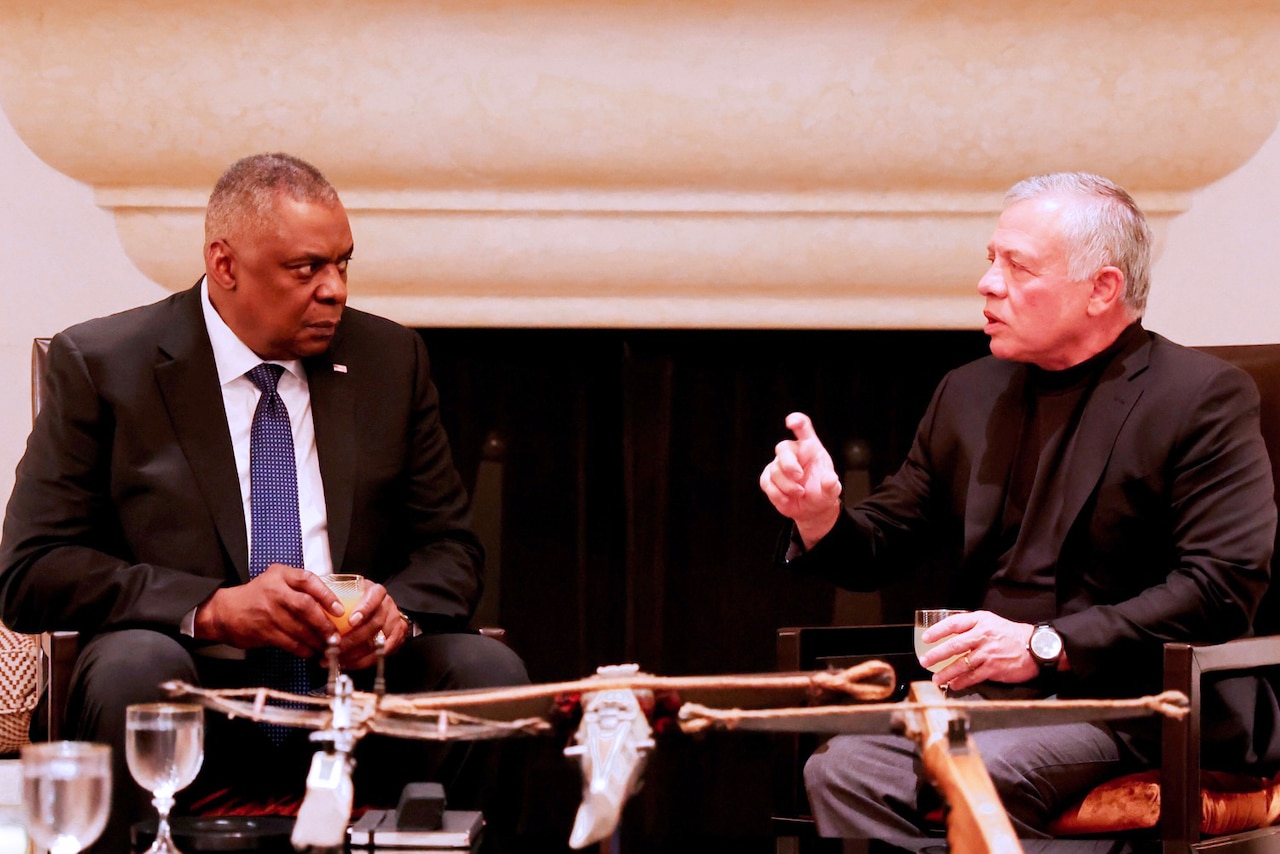 Two men sit facing one another.