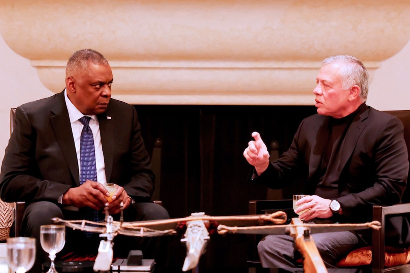 Two men sit facing one another.