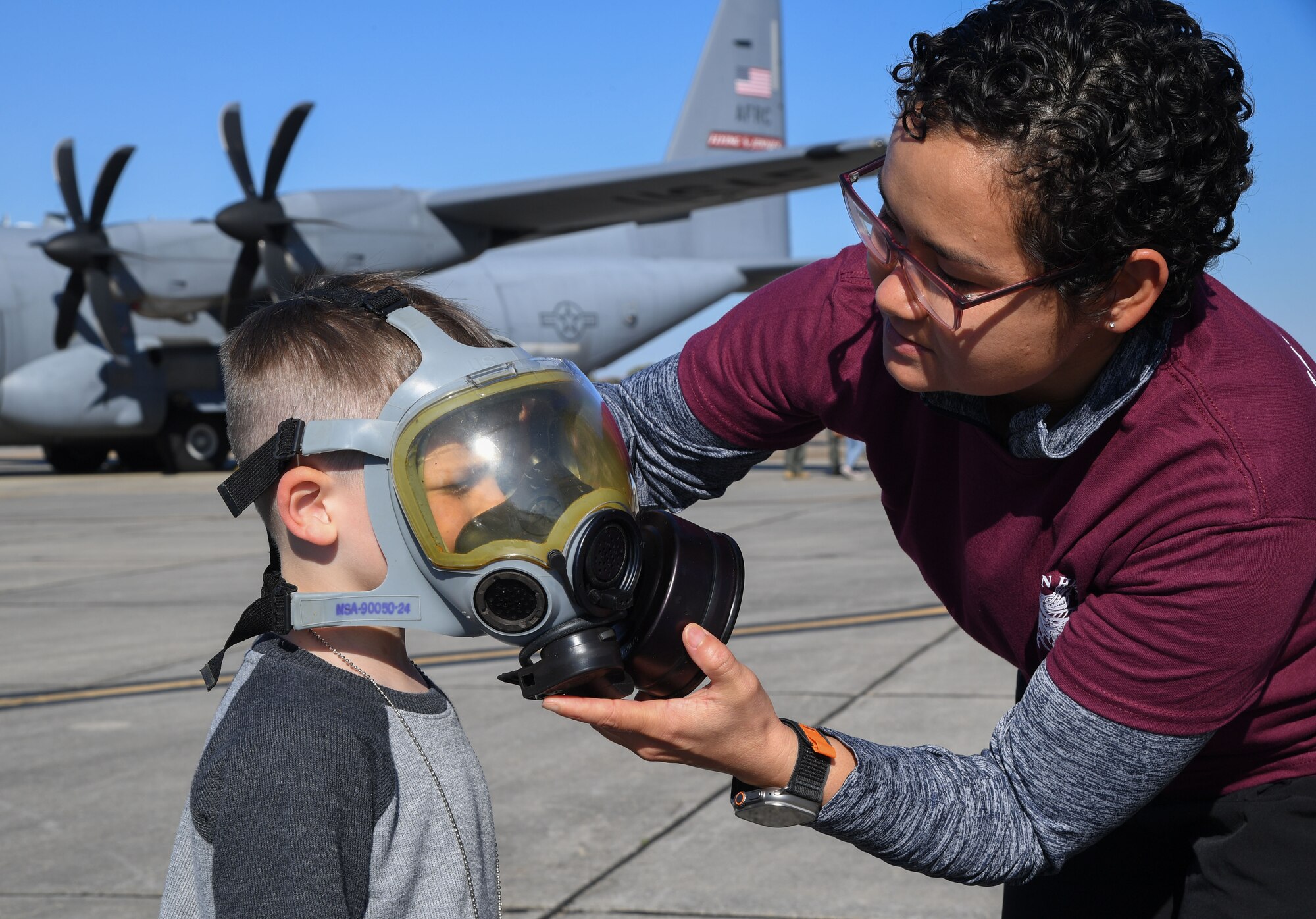 U.S. Air Force Airman 1st Class Christina Piper, 336th Training Squadron student, secures a gas mask on Benjamin Kuc, son of Lt. Col. Katherine Kuc, 81st Force Support Squadron commander, during Operation Hero at Keesler Air Force Base, Mississippi, March 4, 2023.