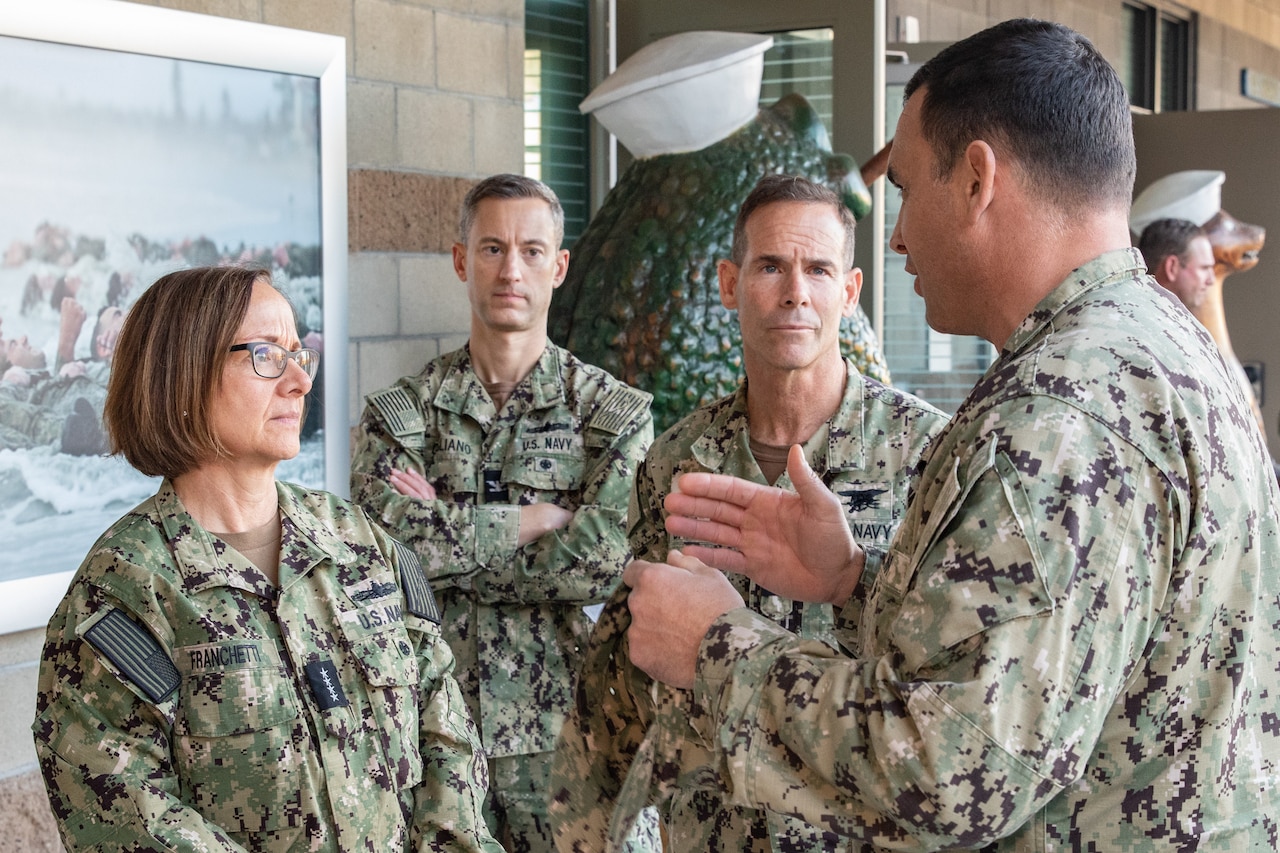 Four people in military uniform hold a discussion.