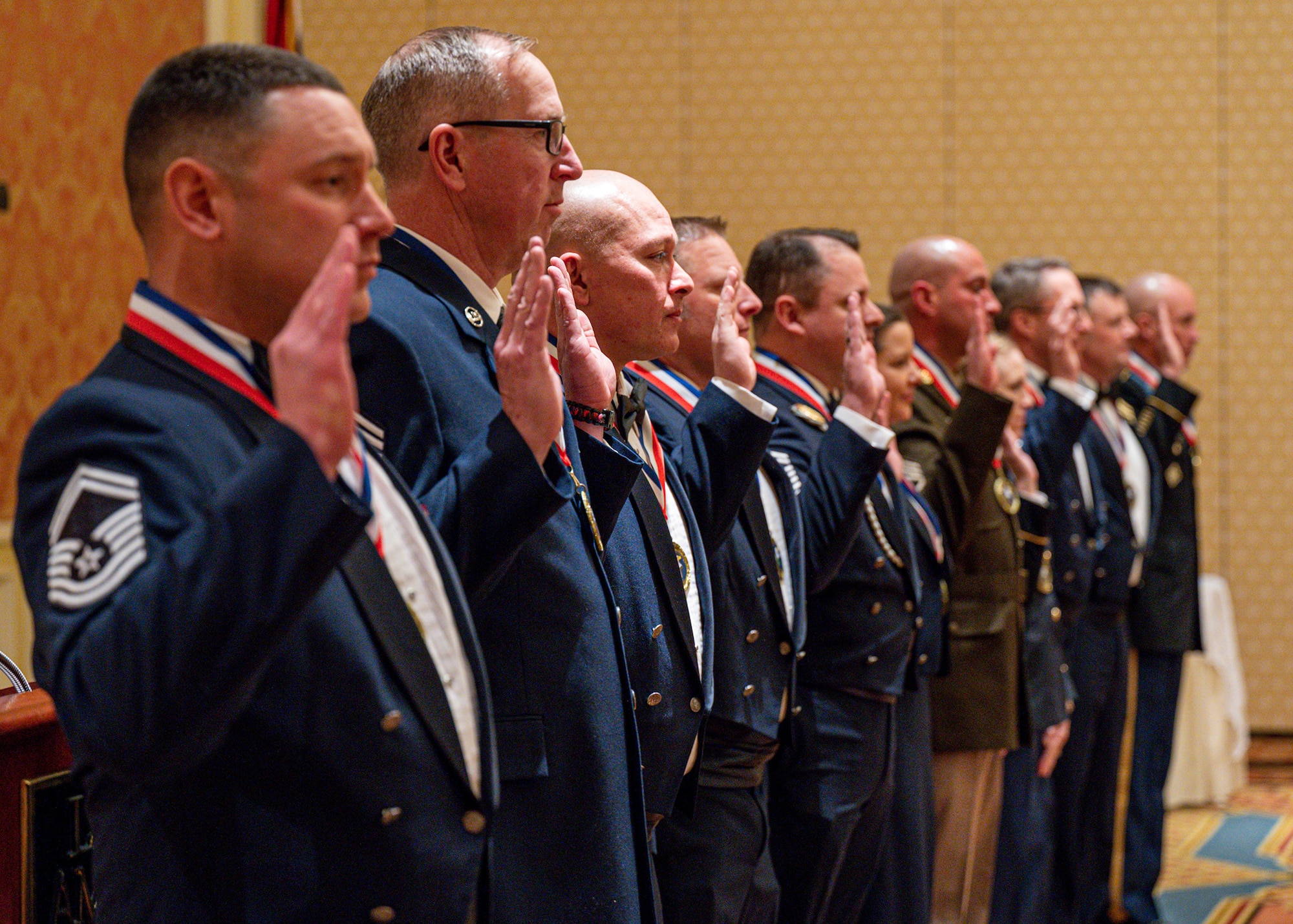 senior enlisted leaders stand with right hand up giving charge