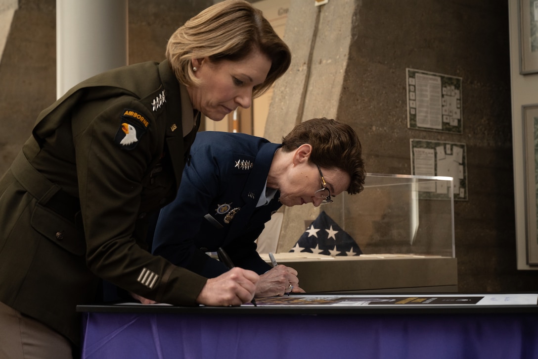 U.S. Army Gen. Laura Richardson, U.S. Southern Command commander, left, and U.S. Air Force Gen. Jacqueline Van Ovost, U.S. Transportation Command commander, sign an event poster before a Women's History Month panel discussion at the Military Women's Memorial in Arlington National Cemetery, Arlington, Va., March 6, 2023.