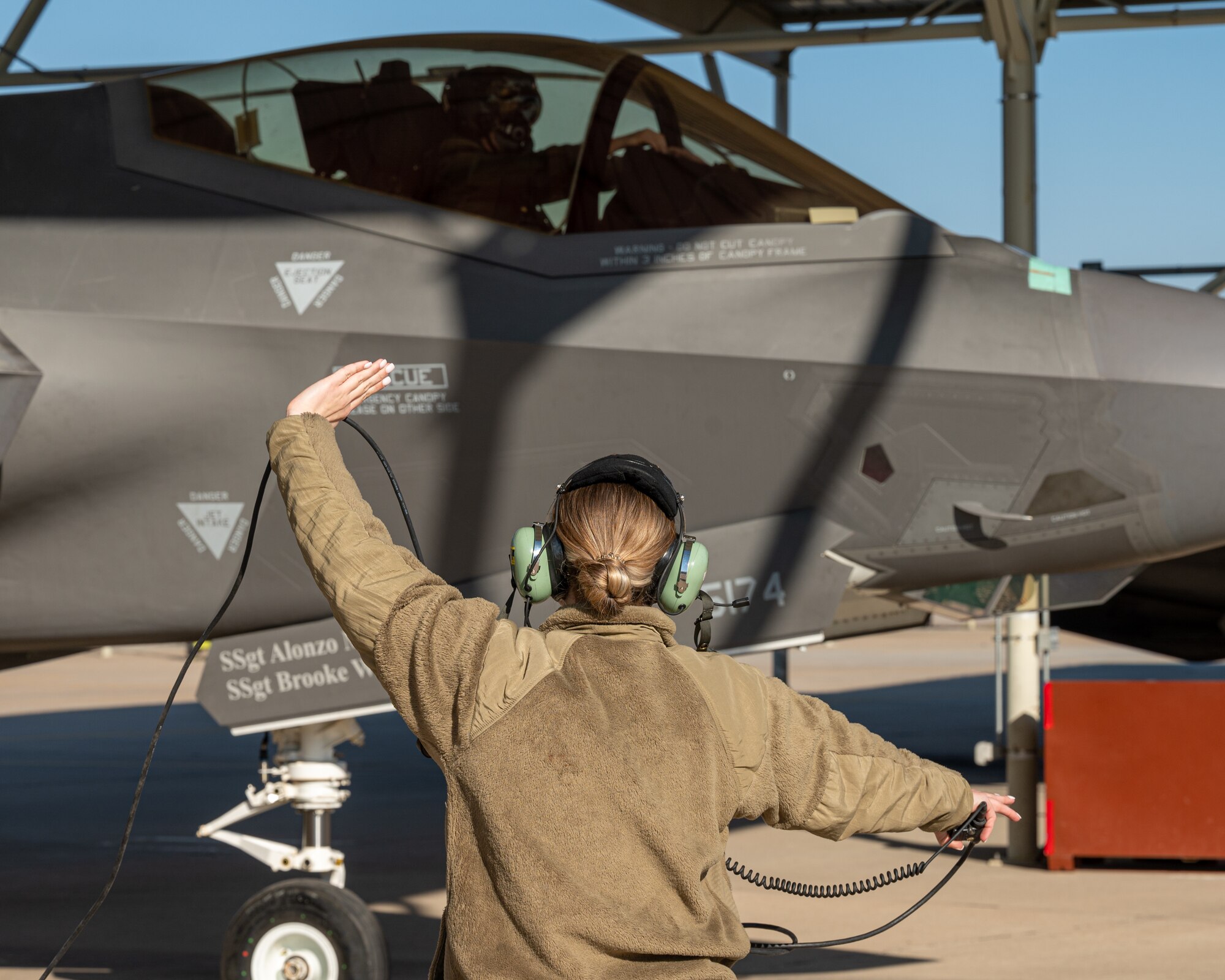 U.S. Air Force Staff Sgt. Brooke Keppler, 63rd Aircraft Maintenance Unit crew chief, communicates with U.S. Air Force Lt. Col. Jeremy Hedges, 944th Fighter Wing F-35 Lightning II instructor pilot, before takeoff, Mar. 3, 2023, at Luke Air Force Base, Arizona.