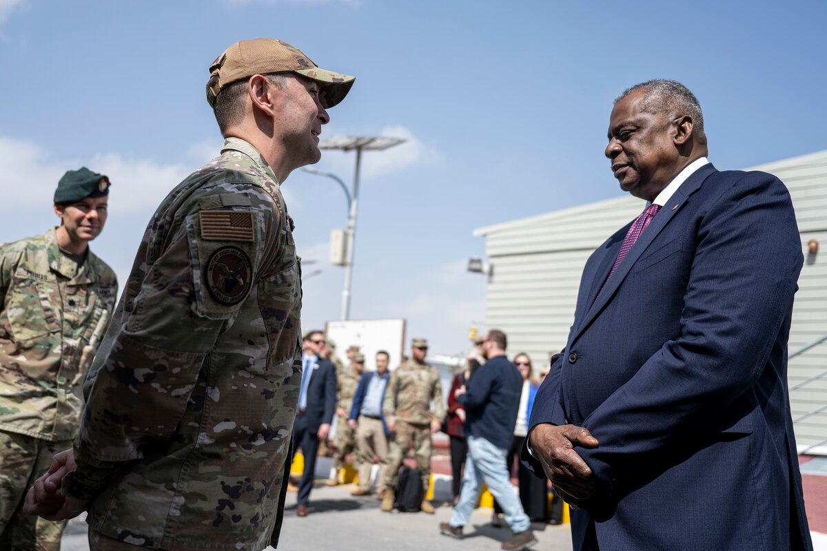 A man in uniform talks with a man in a suit.