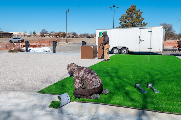 Contractors install turf grass in the new Food Truck Park Feb. 10, 2023, at McConnell Air Force Base, Kansas. The new Food Truck Park will have a gazebo for seating, turf grass for kids to play on and chargers for people that own an electric vehicle. The Food Truck Park will offer Team McConnell an alternate to off base food options. (U.S. Air Force photo by Airman 1st Class Brenden Beezley)