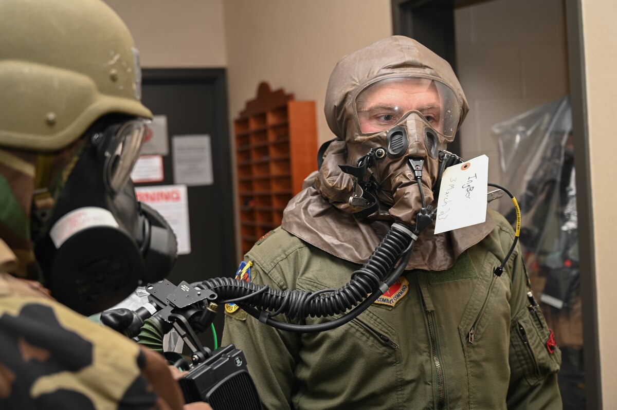An A-10C Thunderbolt II pilot assigned to the 104th Fighter Squadron awaits as an aircrew flight equipment technician performs decontamination procedures March 3, 2023, during a readiness exercise at Martin State Air National Guard Base, Maryland.