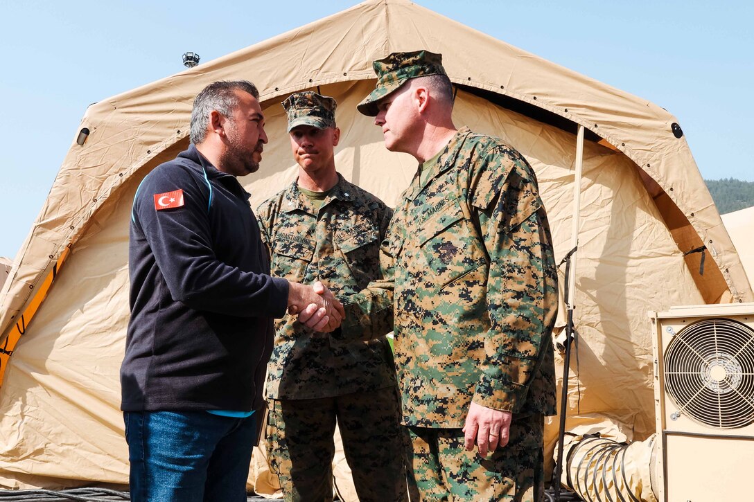 A military officer greets and shakes hands with a civilian.