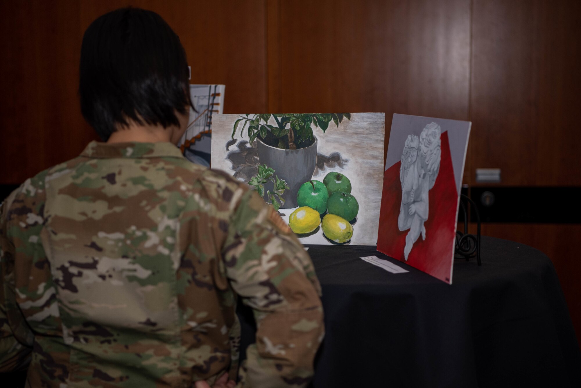 A service member views artwork on display.