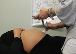 Certified Nurse Midwife, Maj. Nicole Sampson, measures baby's heart rate during the health assessment portion of a Centering Pregnancy session at Blanchfield Army Community Hospital in 2018. Blanchfield is resuming Centering Pregnancy, which brings expectant mothers together in healthcare groups of 8 to 12 women, for 10 two-hour sessions, to share in their prenatal healthcare journey. Each session features a health assessment, interactive learning and community support. U.S. Army photo by Maria Yager.