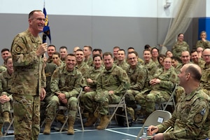 An individual standing with a microphone speaks to a seated crowd