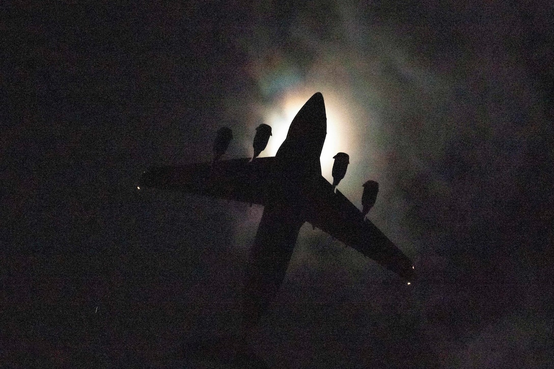 An aircraft flies in a dark sky.