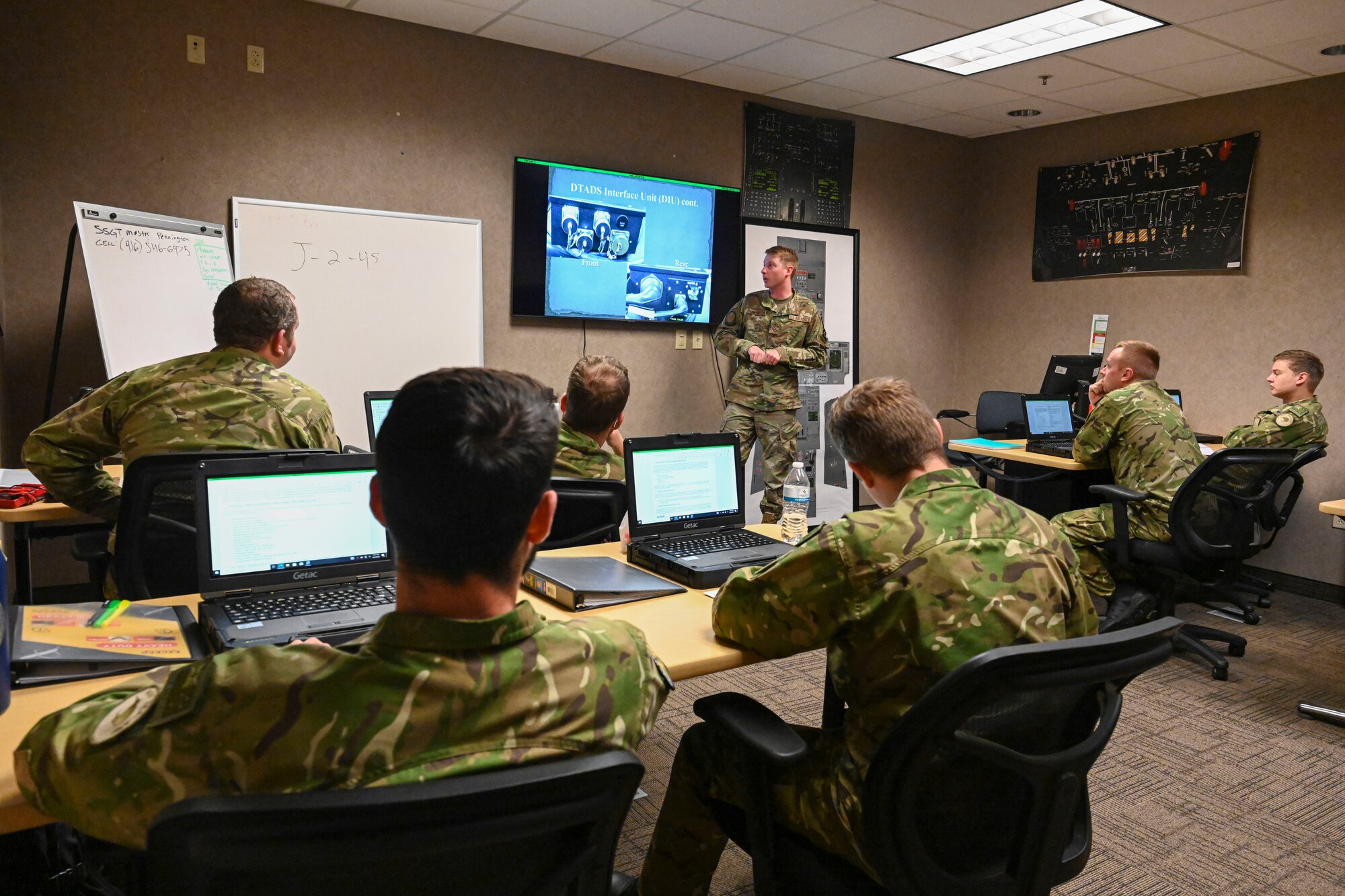 Airman sit in class receiving instruction from a teacher