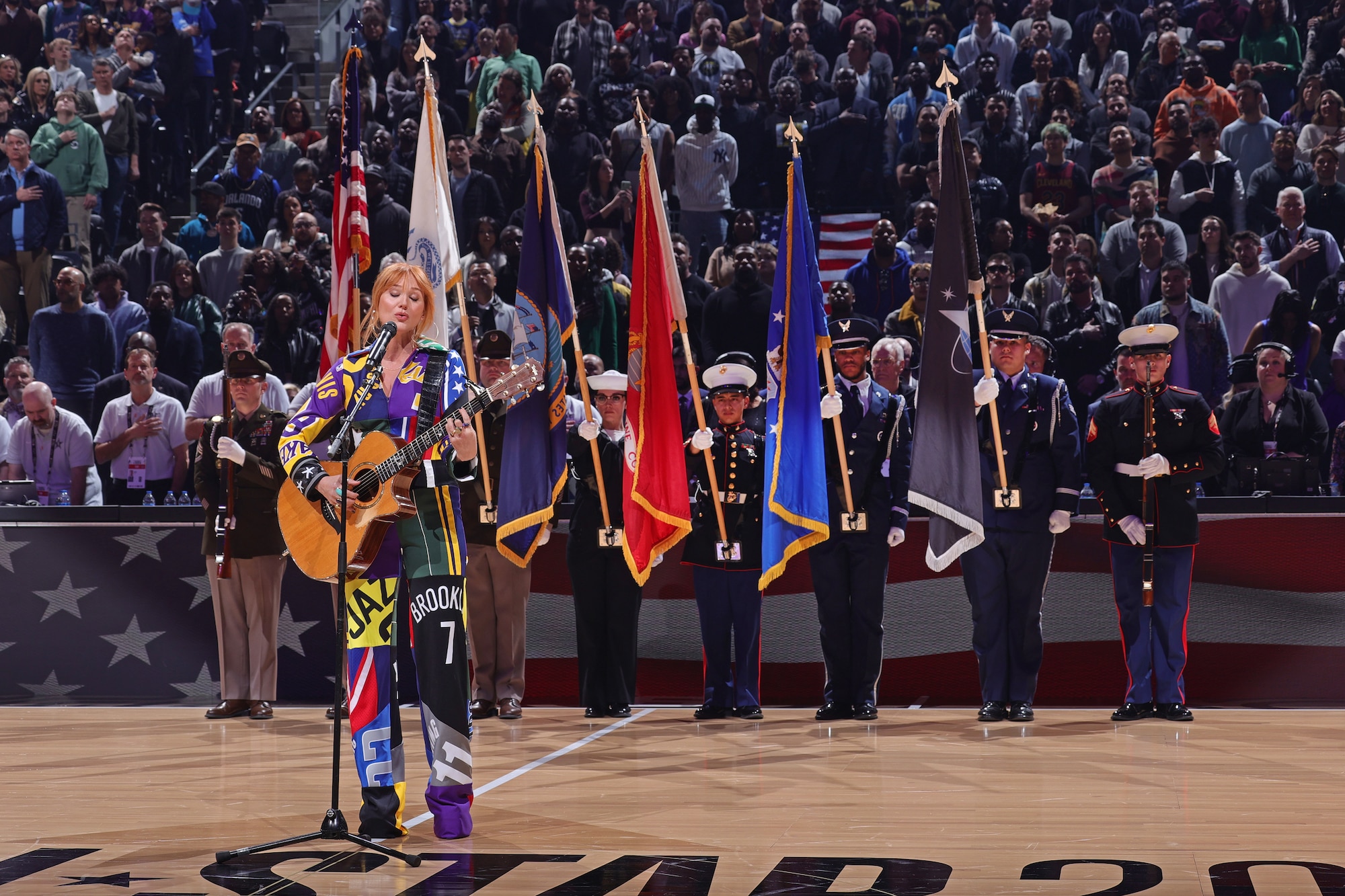 Singer Jewel and a joint service color guard including Senior Airman Tyrone Treadwell, holding the Air Force flag, and Senior Airman Mason Gonzales, holding the Space Force flag, during the national anthem ahead of the NBA All-Star Game