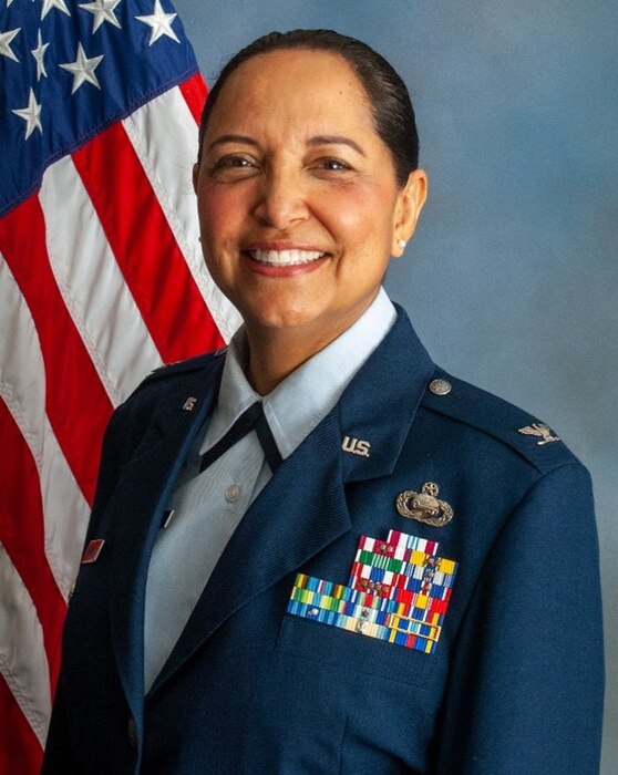 Col. Corona sits in front of an American flag smiling for an official photo