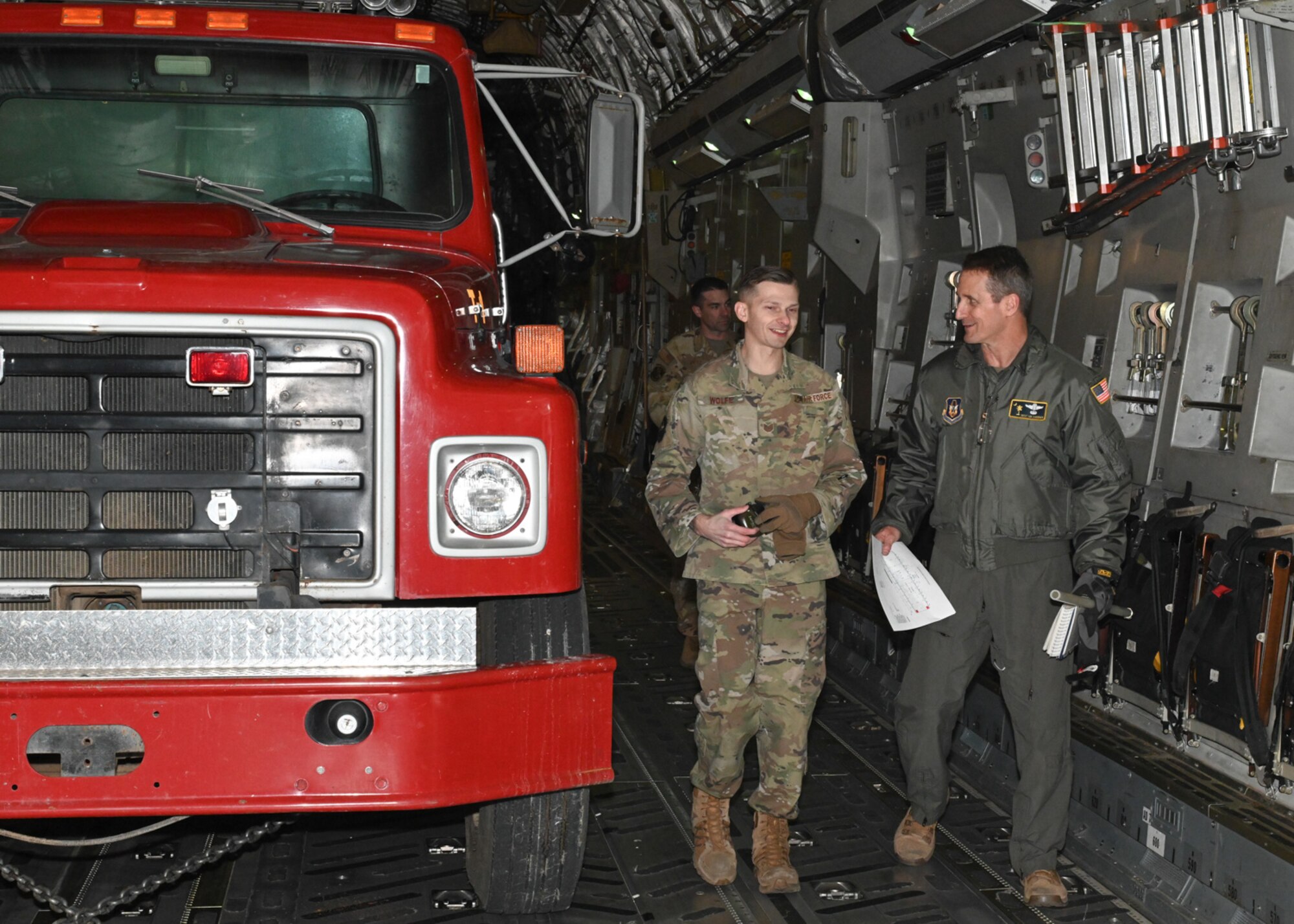 Service members from the 509th Bomb Wing and 437th Airlift Wing attach chains to a firetruck on board a C-17 at Whiteman Air Force Base, Missouri, February 10, 2023. The 437th Airlift Wing occasionally completes missions moving donated cargo through the Denton Program, which enables the DOD to provide logistical support for charitable organizations. (U.S. Air Force photo by Senior Airman Nash Truitt)