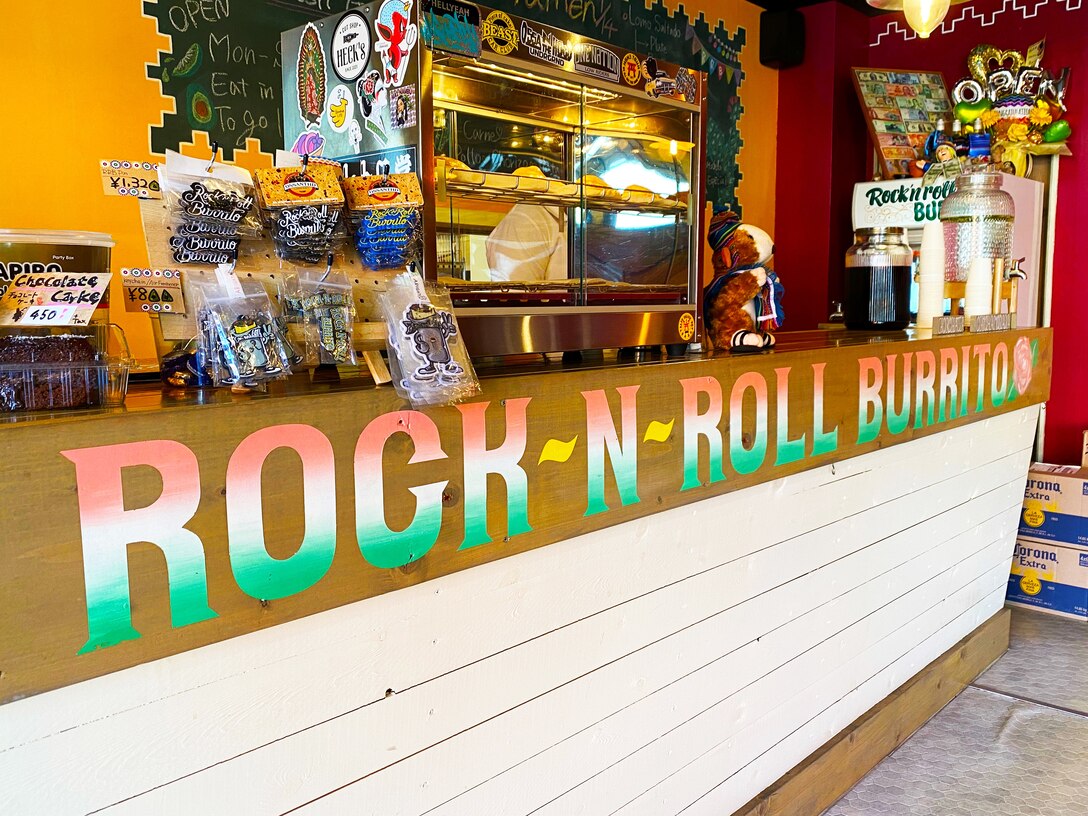 Colorful burrito-centric magnets and keychains adorn the register area in Rock-N-Roll Burrito, a family-owned Mexican cantina-style establishment located near Naval Air Facility Atsugi. Featured near the register is a glass case filled with freshly made empanadas, and surrounding it is other Latin American specialties like Tres Leche cake, and horchata, a sweetened plant-based milk.