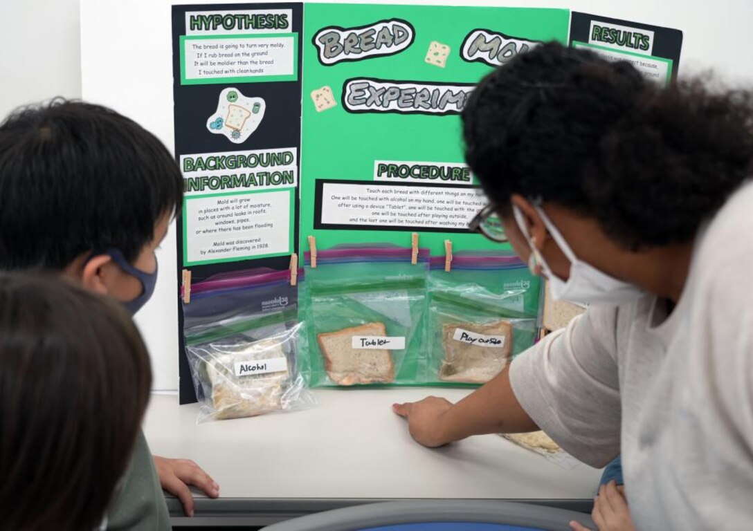 Students at the AmerAsia School in Okinawa examine a science fair project that demonstrates the importance of hand washing via mold growth. The school is home to 63 students, most being half Japanese and half American. Two Engineers, JED representatives Dr. Rex Mols, OAO’s Host Nation Branch Chief, and Brian Ciccocioppo, Resident Engineer of Okinawa’s Torii Office, have volunteered their own time to encourage interest in science, technology, engineering, and math (STEM) at the local school as a way of giving back to the local Okinawan community.