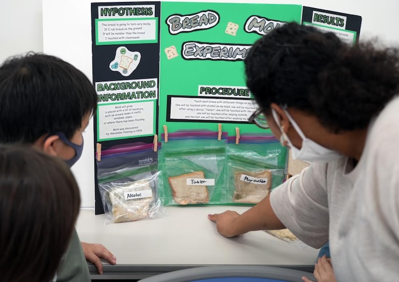 Students at the AmerAsia School in Okinawa examine a science fair project that demonstrates the importance of hand washing via mold growth. The school is home to 63 students, most being half Japanese and half American. Two Engineers, JED representatives Dr. Rex Mols, OAO’s Host Nation Branch Chief, and Brian Ciccocioppo, Resident Engineer of Okinawa’s Torii Office, have volunteered their own time to encourage interest in science, technology, engineering, and math (STEM) at the local school as a way of giving back to the local Okinawan community.