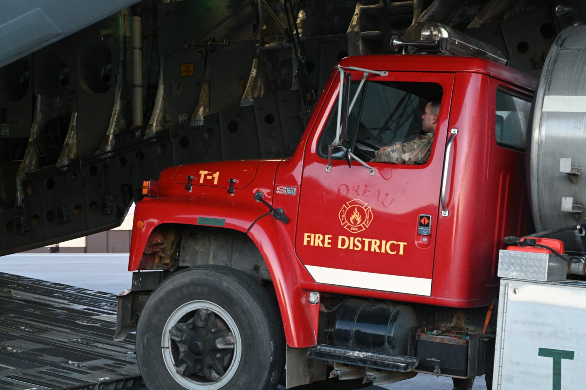 Service members from the 509th Bomb Wing and 437th Airlift Wing attach chains to a firetruck on board a C-17 at Whiteman Air Force Base, Missouri, February 10, 2023. The 437th Airlift Wing occasionally completes missions moving donated cargo through the Denton Program, which enables the DOD to provide logistical support for charitable organizations. (U.S. Air Force photo by Senior Airman Nash Truitt)