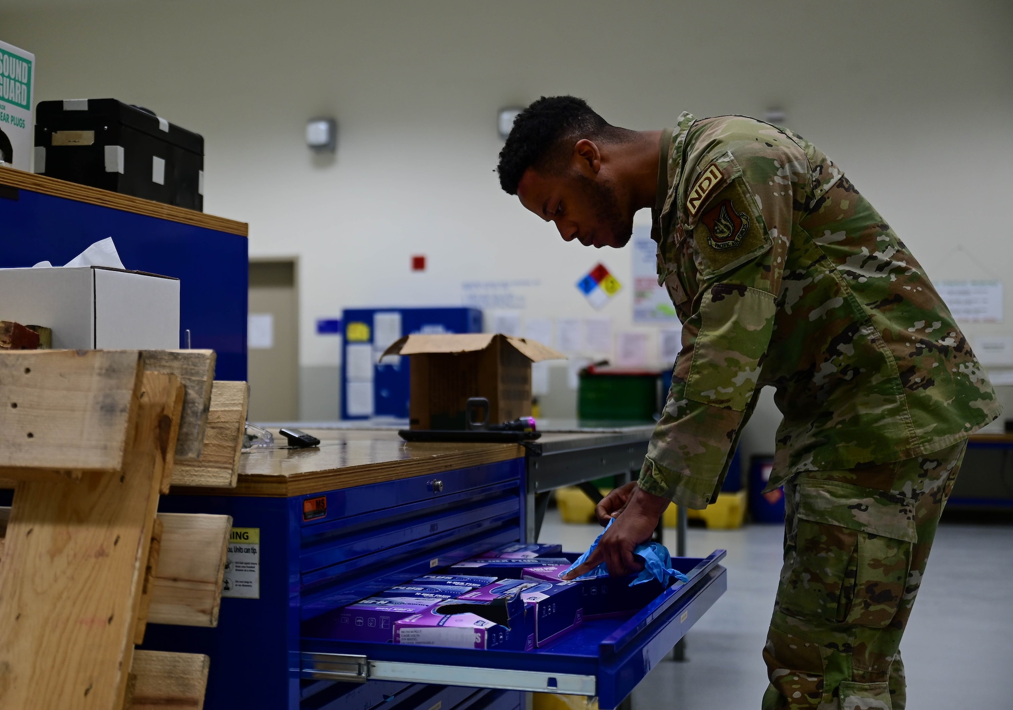 Airman 1st Class Jaylin Tripp, 8th Maintenance Squadron nondestructive inspection specialist, reaches for gloves before testing a piece of aircraft equipment at Kunsan Air Base, Republic of Korea, Mar. 6, 2023.