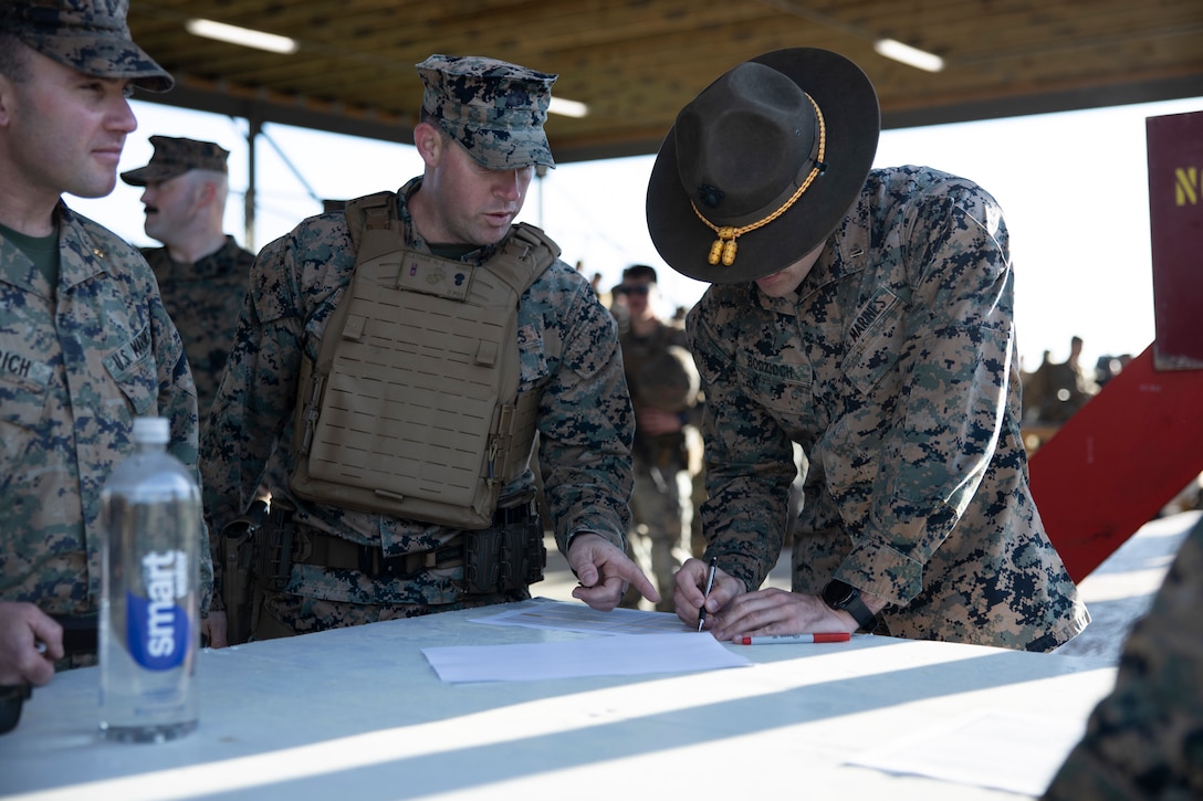 U.S. Marine Corps Gunner Chris Latham, center, training company gunner with Marine Corps Security Force Regiment, signs in with 1st Lt. John Bodzioch, right, executive officer with Weapons Training Battalion Quantico, Marine Corps Base Quantico, Virginia,  during day one of the 2023 Marine Corps Marksmanship Competition East on Stone Bay, Marine Corps Base (MCB) Camp Lejeune, North Carolina, March 6, 2023. All Marines east of the Mississippi were invited to attend this annual competition to increase their combat effectiveness and lethality using MCB Camp Lejeune's premier ranges. (U.S. Marine Corps photo by Cpl. Antonino Mazzamuto)