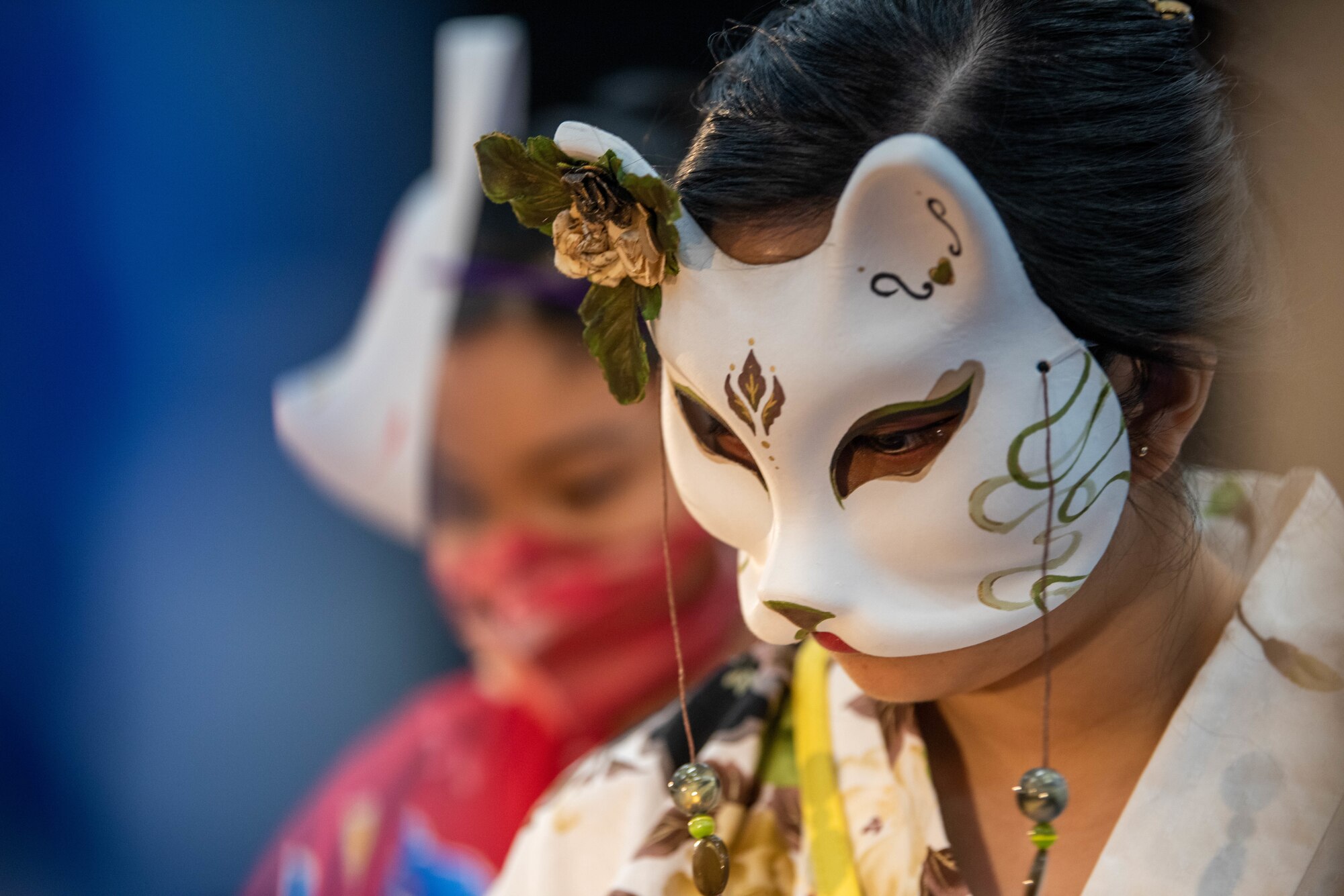An Asian girl wears a cat mask.