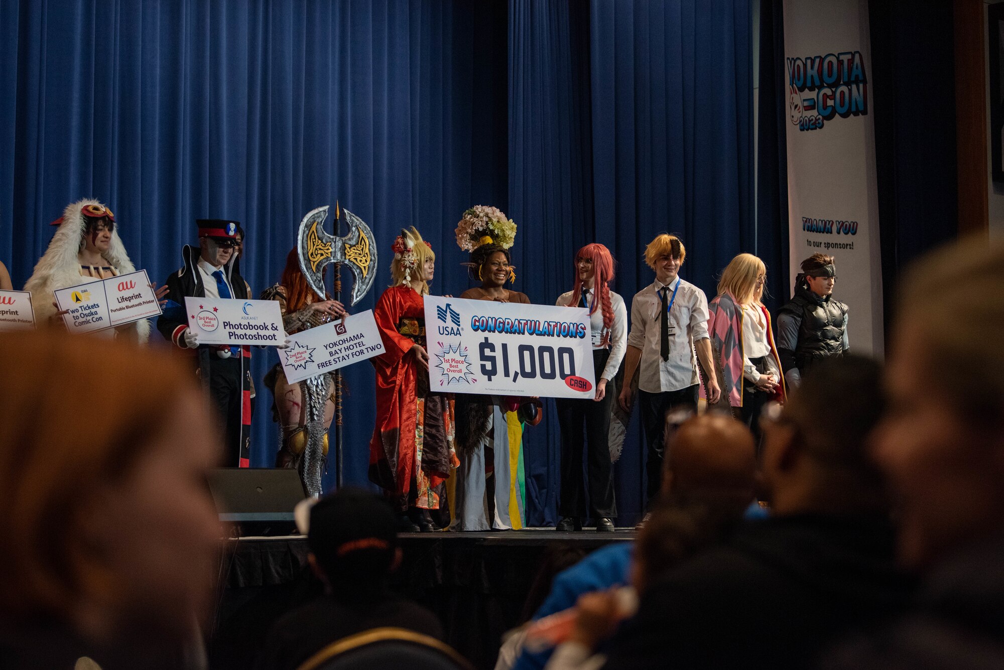 People dressed in costumes stand on a stage.