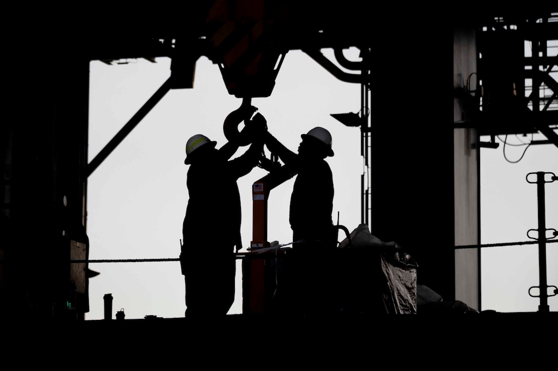 Sailors prepare a crane to offload humanitarian supplies