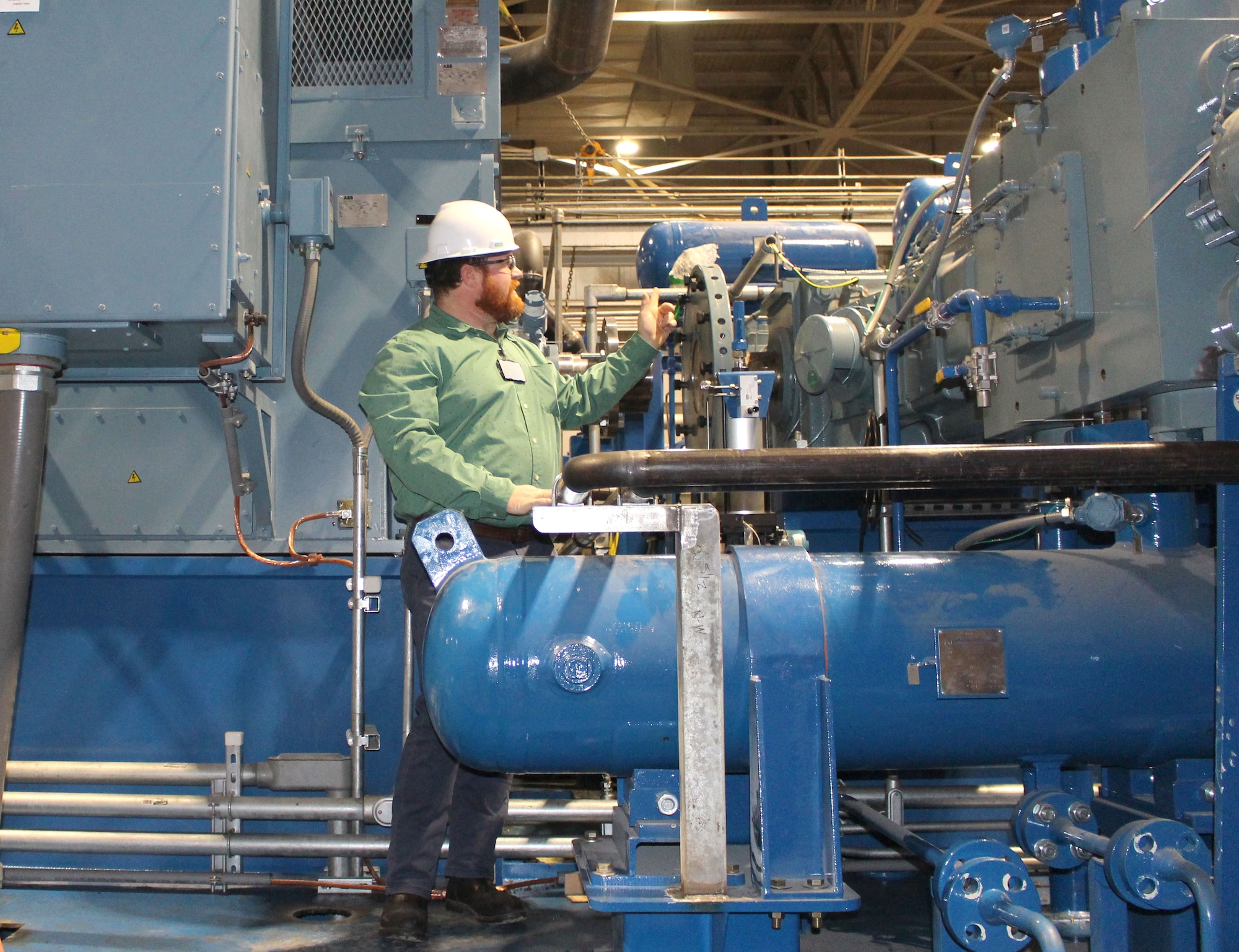 A man in a green shirt looks to the right and takes a closer look at some of the equipment recently installed to improve high-pressure air capacity to the test cells at Arnold Air Force Base.