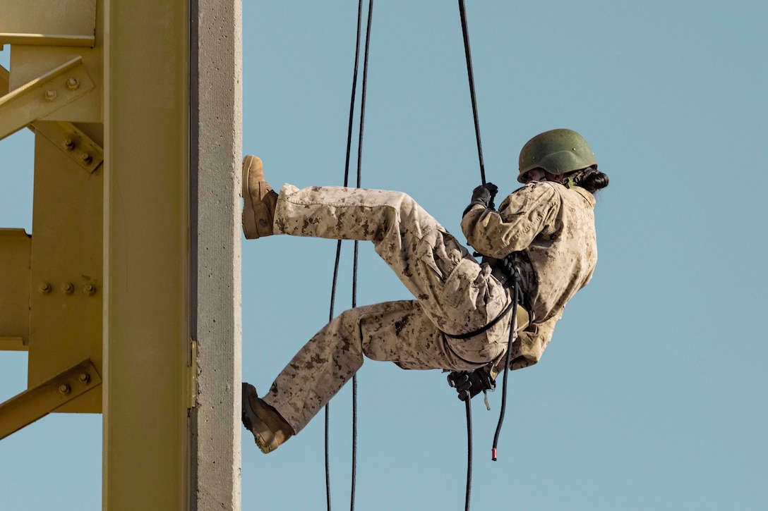 A Marine rappels down a tower.