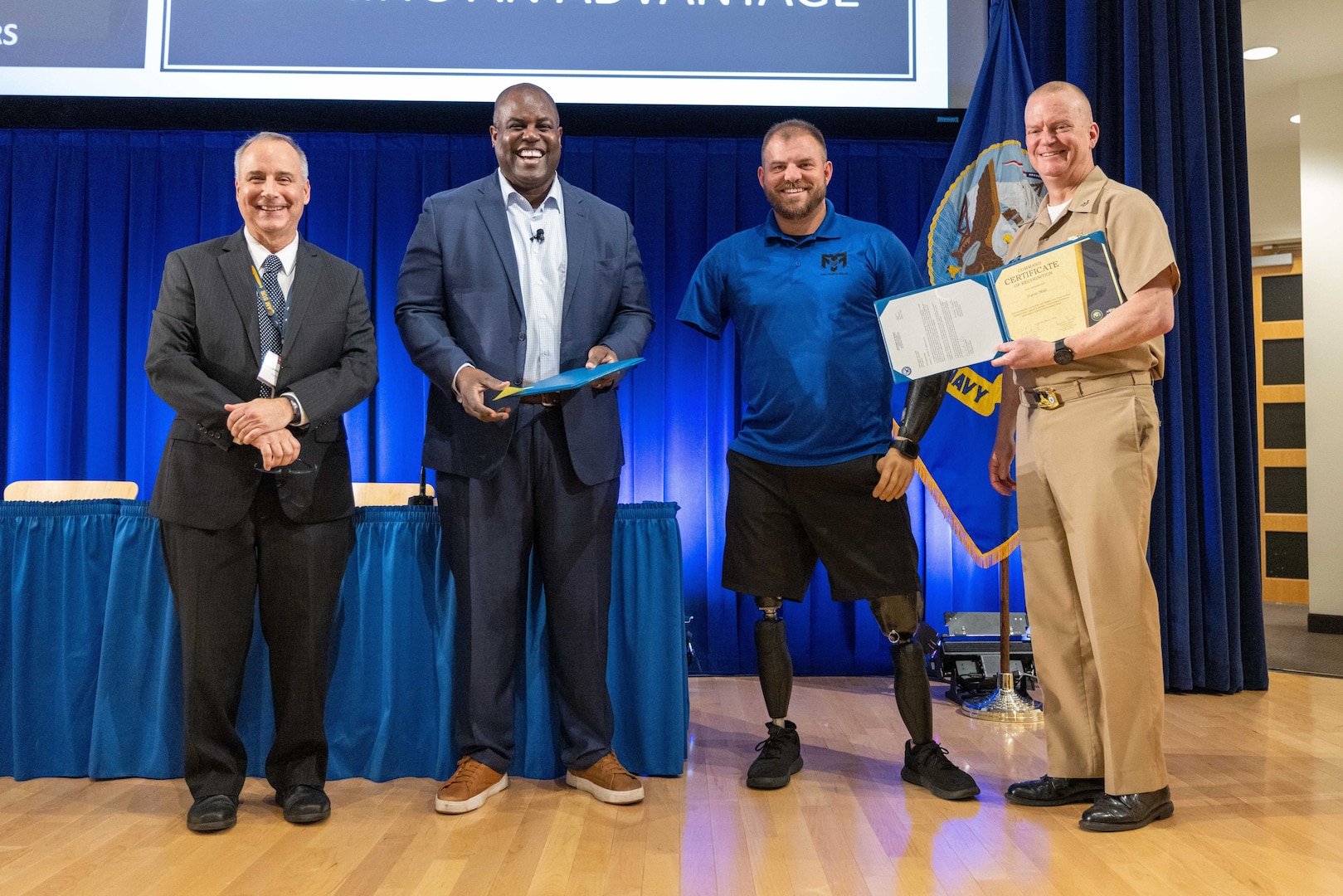 Naval Surface Warfare Center, Carderock Division's Technical Director Larry Tarasek (far left) and Commanding Officer Capt. Todd E. Hutchison (far right) present certificates of recognition to Reggie Rivers (middle left) and Travis Mills (middle right), thanking them for being guest speakers during Carderock's 21st Century Workforce: A Leadership in a Diverse Environment Event (LDEE) in West Bethesda, Md., on March 1. (U.S. Navy photo by Devin Pisner)
