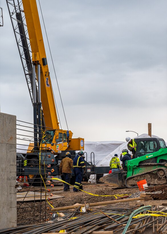 Construction workers are pictured using heavy equipment operations around the construction site.