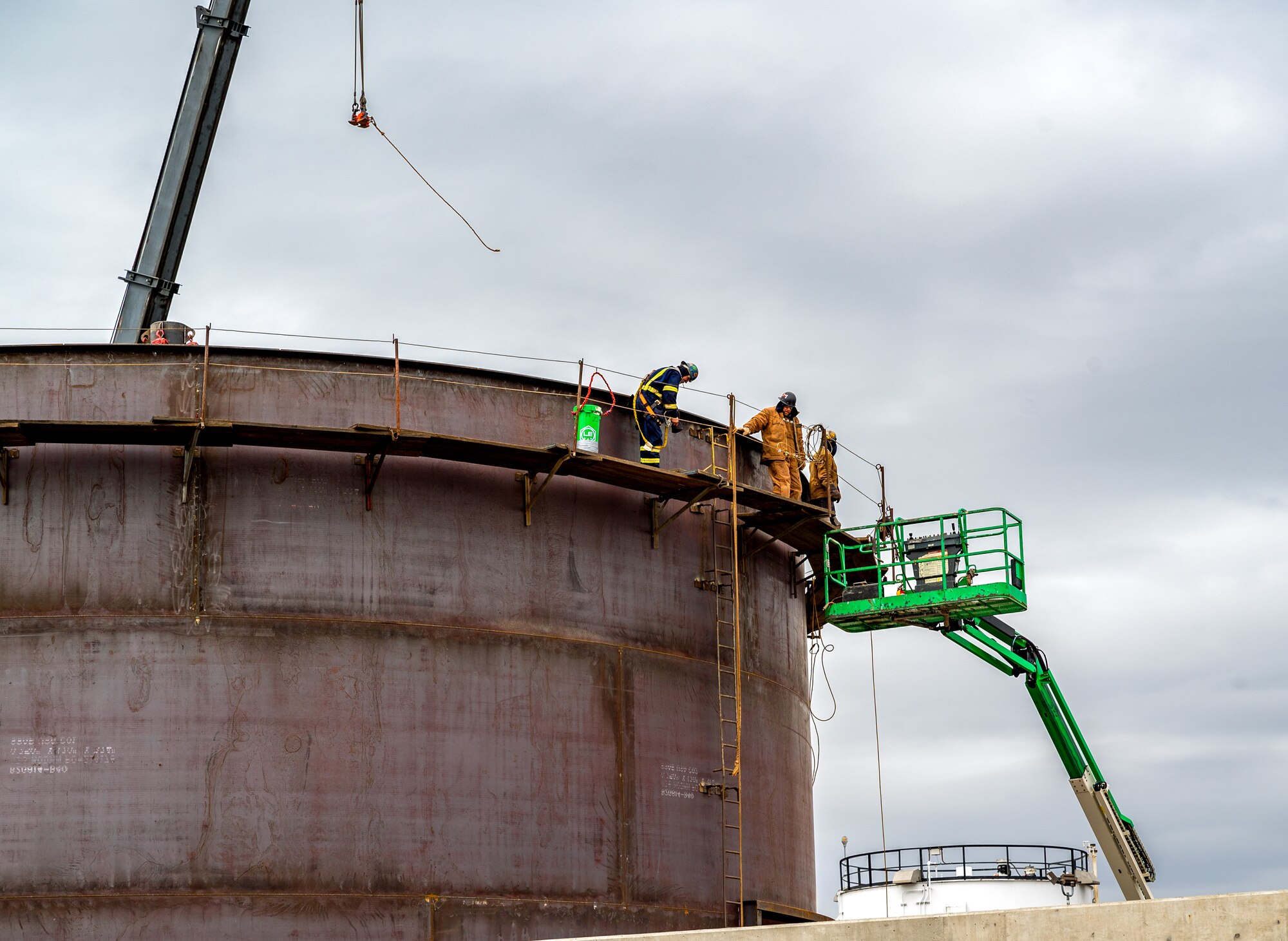Construction workers use a lift to climb onto a new fuel tank being built on Niagara Falls Air Reserve Station.
