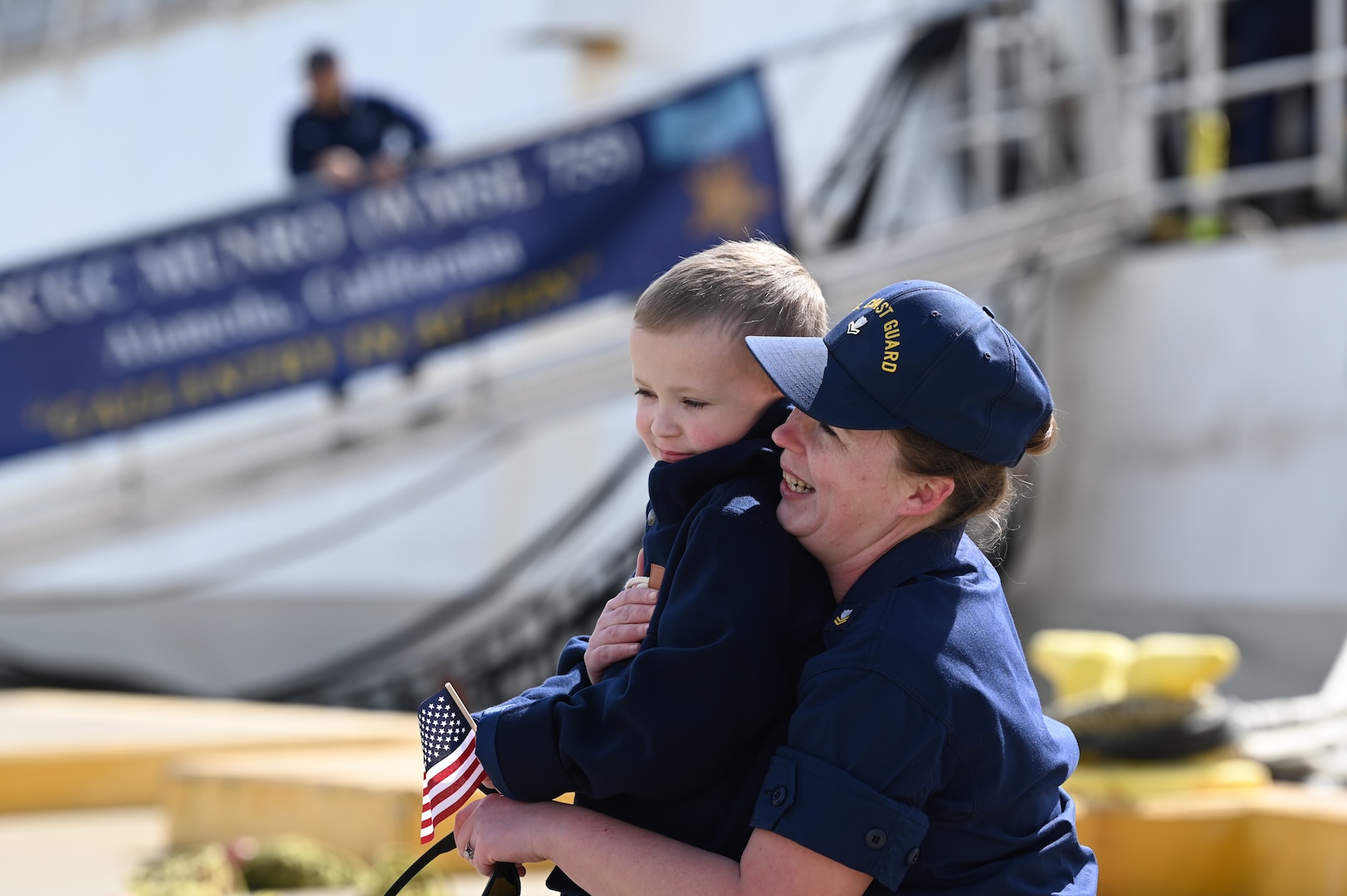 Petty Officer 2nd Class Hannah Capps hugs her son after the Coast Guard Cutter Munro (WMSL 755) returned to Alameda, Calif., March 6, 2023, following a 105-day, 11,500-nautical mile Alaska Patrol. Munro partnered with NOAA Office of Law Enforcement personnel to conduct 24 boardings of commercial fishing vessels with the goal of enforcing sustainable fishing practices and ensuring compliance with federal regulations. U.S. Coast Guard Cutter Munro returns from Alaska Patrol. U.S. Coast Guard photo by Chief Petty Officer Matthew S. Masaschi.