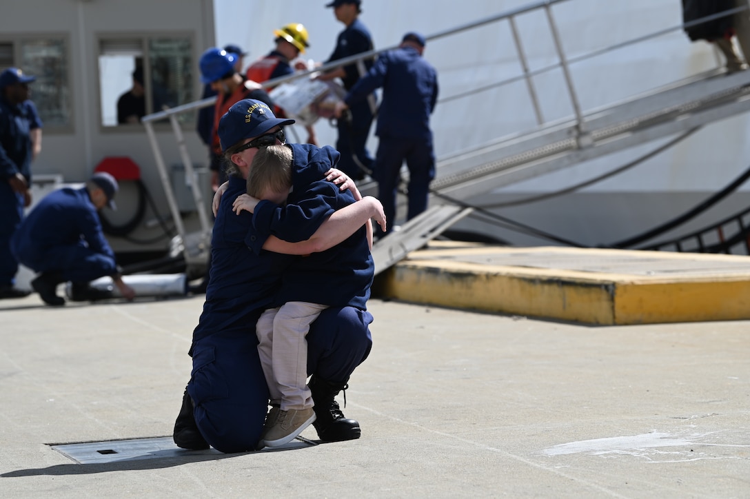 Petty Officer 2nd Class Hannah Capps hugs her son after the Coast Guard Cutter Munro (WMSL 755) returned to Alameda, Calif., March 6, 2023, following a 105-day, 11,500-nautical mile Alaska Patrol. Munro partnered with NOAA Office of Law Enforcement personnel to conduct 24 boardings of commercial fishing vessels with the goal of enforcing sustainable fishing practices and ensuring compliance with federal regulations. U.S. Coast Guard Cutter Munro returns from Alaska Patrol. U.S. Coast Guard photo by Chief Petty Officer Matthew S. Masaschi.