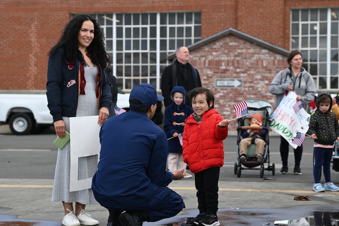 Petty Officer 1st Class Robert Molina greets his family on the pier after the Coast Guard Cutter Munro (WMSL 755) returned to Alameda, Calif., March 6, 2023, following a 105-day, 11,500-nautical mile Alaska Patrol. Munro partnered with NOAA Office of Law Enforcement personnel to conduct 24 boardings of commercial fishing vessels with the goal of enforcing sustainable fishing practices and ensuring compliance with federal regulations. U.S. Coast Guard photo by Chief Petty Officer Matthew S. Masaschi.