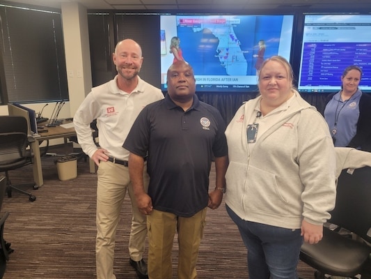 Three people standing in emergency operations center.
