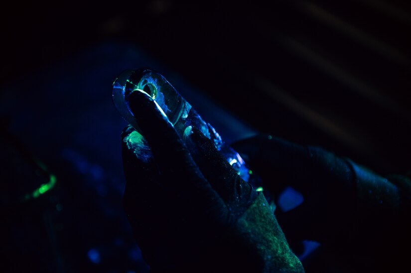 Close up of hands holding tool in blacklight