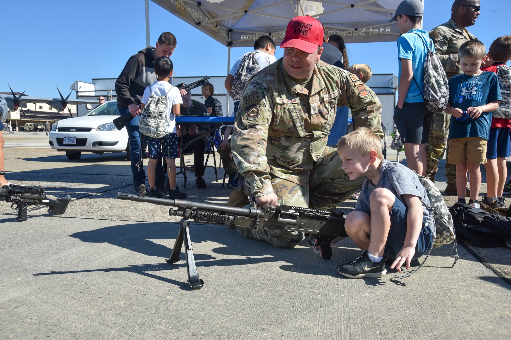 An Airman shows a kid one of the weapons used in a deployed environment
