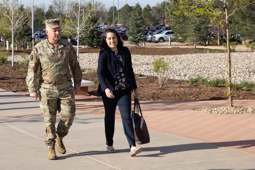 A service member and a civilian walk along a sidewalk.