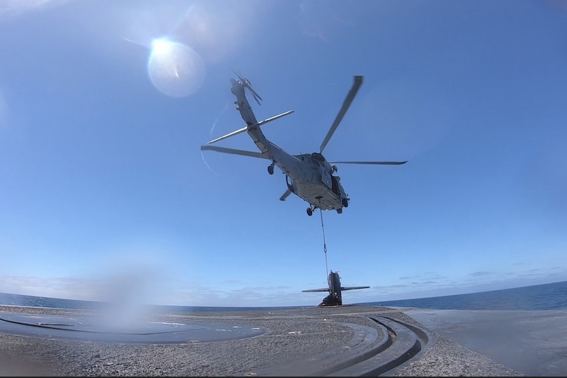 A helicopter hovers above a ship.