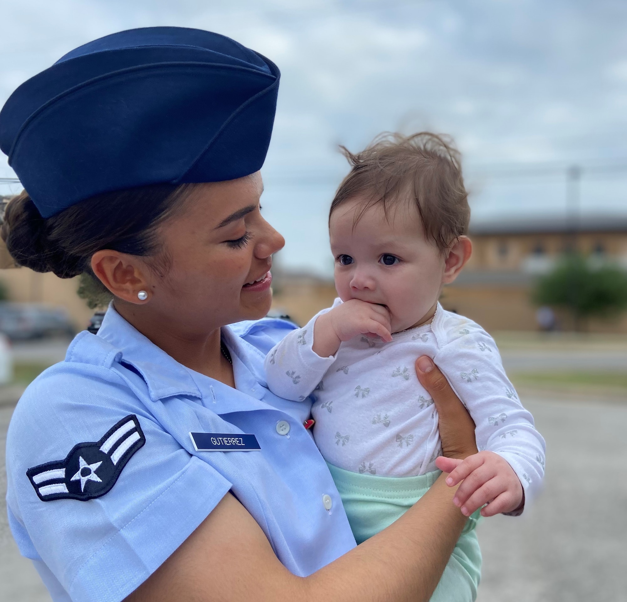 Female Airman in blue dress uniform holds her baby daughter
