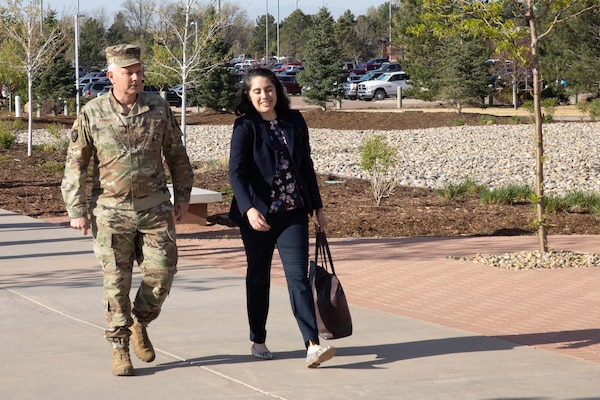 A service member and a civilian walk along a sidewalk.