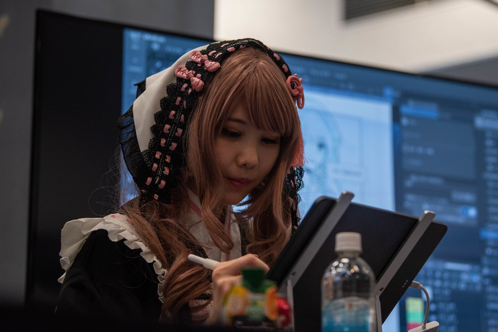 A Japanese woman wearing a costume draws on a digital pad.